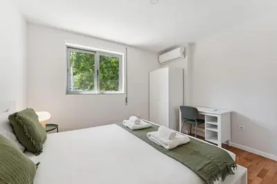 a white bedroom with a large bed and a desk at GuestReady - Fantastic family home in Salgueiros in Porto