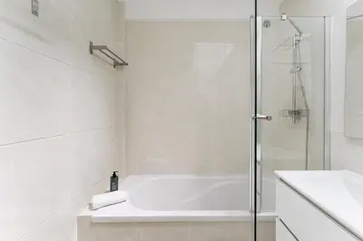a white bathroom with a shower and a bath tub at GuestReady - Fantastic family home in Salgueiros in Porto