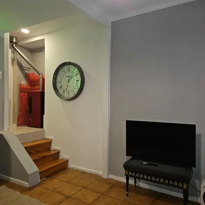 a clock on a wall with a piano and a television at Monte Lapa 38 in Porto