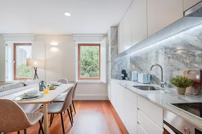 a kitchen with white cabinets and a table with chairs at Balcony Retreat | Porto Urban Flats in Porto