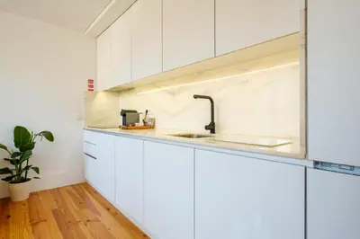 a kitchen with white cabinets and a sink at Porto Santo Ildefonso Central Loft in Porto