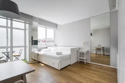 a white bedroom with a bed and a table at Trindade Duo Apartments in Porto
