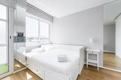a white bedroom with a large white bed and a window at Trindade Duo Apartments in Porto