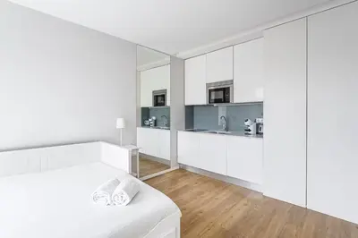 a white bedroom with white cabinets and a bed at Trindade Duo Apartments in Porto