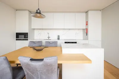a kitchen with a wooden table and white cabinets at Gaia Land Sea View Apartment in Vila Nova de Gaia
