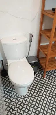a white toilet in a bathroom with a black and white floor at Trindade Apartment in Porto