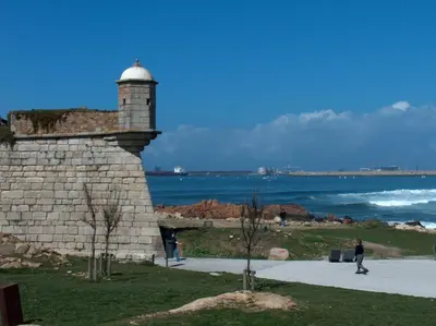 a lighthouse with people walking on a sidewalk near the ocean at Oportolazaro Premium Downtown Porto in Porto