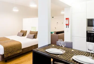 a hotel room with a bed and a table with plates and wine glasses at Oportolazaro Premium Downtown Porto in Porto