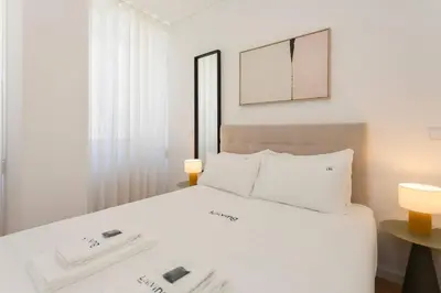 a bedroom with a white bed with two lamps and a mirror at Liiiving in Porto - Invictus Bolhao Market in Porto
