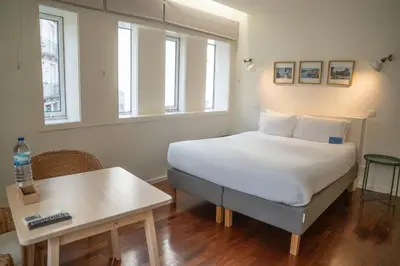 a bedroom with a bed and a table and windows at Oporto Riverside Rooftop in Porto