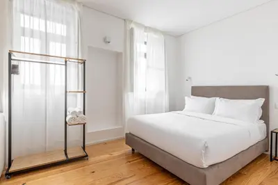 a bedroom with a white bed and windows at Filigrana Apartments in Porto