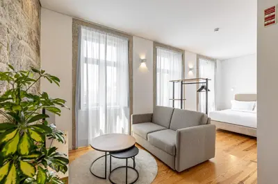 a living room with a couch and a chair and a bed at Filigrana Apartments in Porto