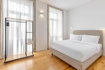 a bedroom with a white bed and a large window at Filigrana Apartments in Porto