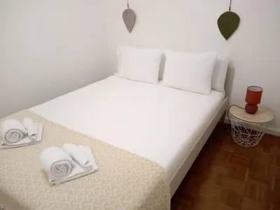 a bed with white sheets and pillows on it at Nice Belmonte Flat in Porto