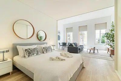 a white bedroom with a large bed and a mirror at Bright Studio in Porto in Porto