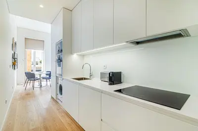 a white kitchen with white cabinets and a sink at Bright Studio in Porto in Porto