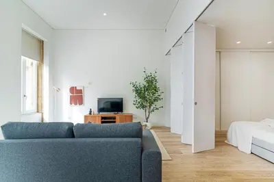 a living room with a blue couch and a bed at Bright Studio in Porto in Porto