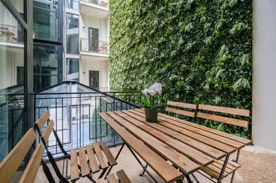 a wooden table and chairs on a balcony with a green wall at Art Deco 14 Luxury Apartment Downtown Metro AC in Porto
