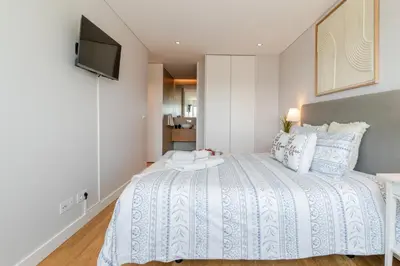 a bedroom with a white bed with a television on the wall at Stylish Home with Balcony & Garage by HostWise in Porto