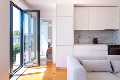 a living room with a couch and a kitchen at Stylish & Sunny 2BR near Heroísmo by LovelyStay in Porto
