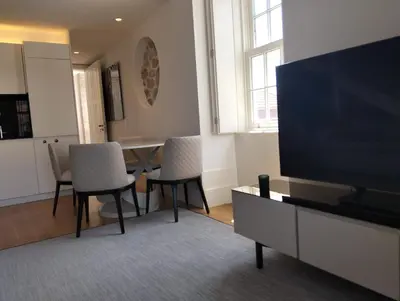 a living room with a table and chairs and a flat screen tv at Timeless Elegance Boutique for two in Porto