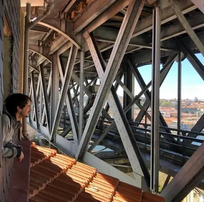 a man standing on a balcony looking at a bridge at Porto Haven - Under the Luís I Bridge in Porto