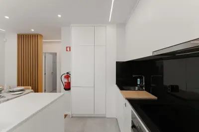 a kitchen with white cabinets and a black counter top at Fernão de Magalhães in Porto