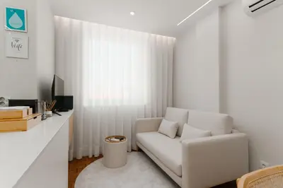 a white living room with a white chair and a television at Fernão de Magalhães in Porto