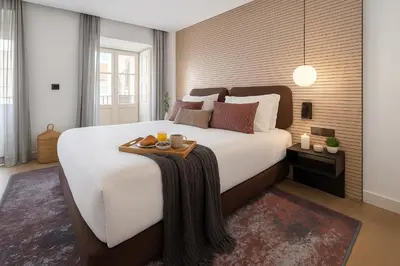 a bedroom with a large bed with a tray of food on it at Aspasios Baixa Apartments in Porto