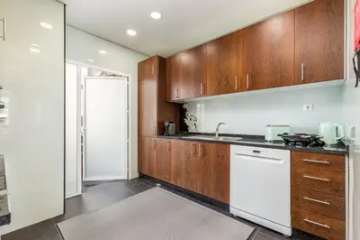 a kitchen with white walls and wooden cabinets at Apartamento de luxo Centro do Porto - ACE Residence in Porto