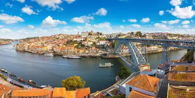 a bridge over a river with boats in a city at Jupiter Porto Hotel - Rooftop & Spa in Porto