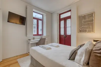 a bedroom with a white bed and a red door at OPORTO GUEST Downtown Escape in Porto