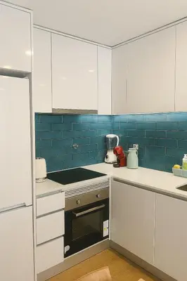 a kitchen with white cabinets and blue tiles at Happy House - Império in Porto