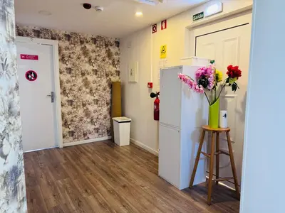 a room with a refrigerator and flowers on a stool at Majestic Hostel Porto in Porto