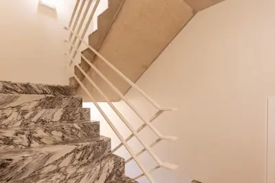 a wooden staircase in a white room with a stone wall at Premium Apartments with Garage by HostWise in Porto