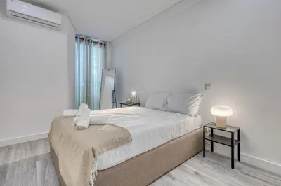 a white bedroom with a large bed and a window at OPORTO GUEST Marquês Square in Porto