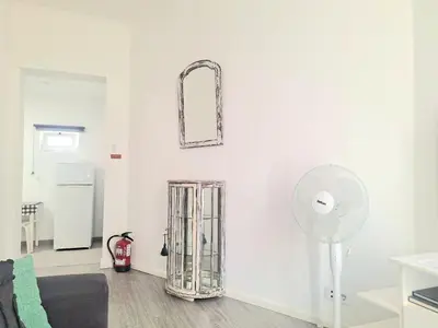 a white living room with a mirror and a fan at porto true confession in Porto