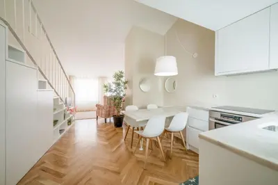 a white kitchen with a table and white chairs at Mouzinho 160 in Porto