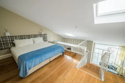 a bedroom with a bed and a staircase with a window at Mouzinho 160 in Porto