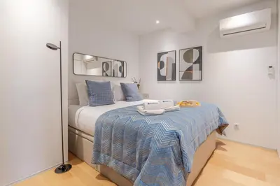 a bedroom with a bed with a blue and white blanket at Stylish Flat with Workspace & Garage by HostWise in Porto