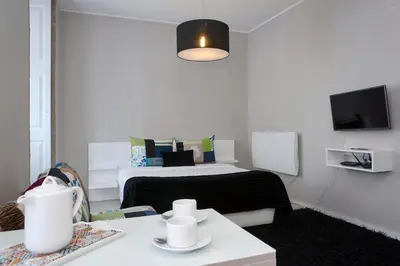 a small white room with a bed and a table at YOUROPO - Clerigos in Porto