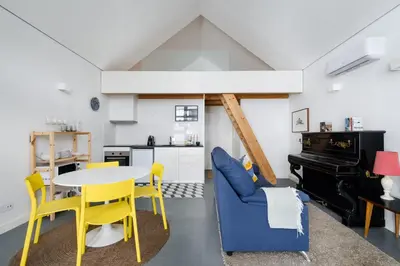 a kitchen and dining room with a table and yellow chairs at Cool Alegria Loft Mezzanine Retreat in Porto