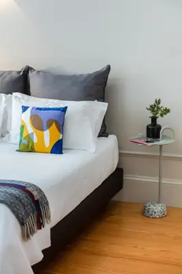 a bedroom with a bed with a pillow and a table at Baumhaus Serviced Living - Art & Design Apartments in Porto