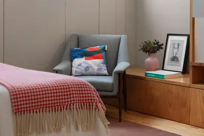 a bedroom with a chair and a table with a pillow at Baumhaus Serviced Living - Art & Design Apartments in Porto