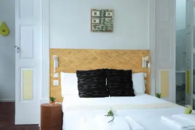 a bedroom with a white bed with a wooden headboard at Studios Faria Guimaraes in Porto