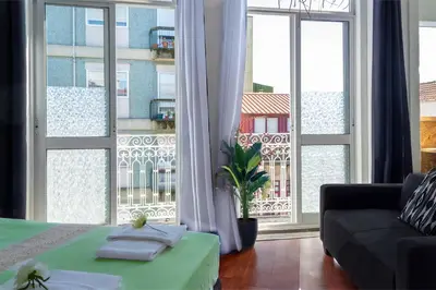 a living room with a bed and a large window at Studios Faria Guimaraes in Porto