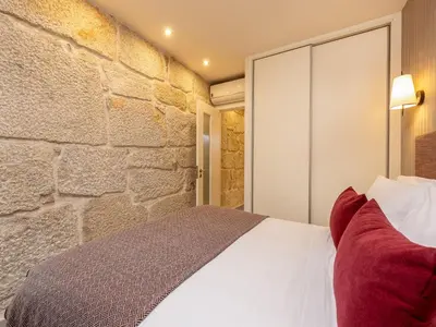 a bedroom with a white bed and a stone wall at Apartment with Balcony for 4 Guests in Porto