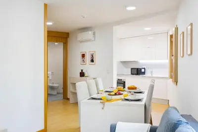 a white kitchen and dining room with a table and chairs at Modern & Central Flat w/ Garage by HostWise in Porto