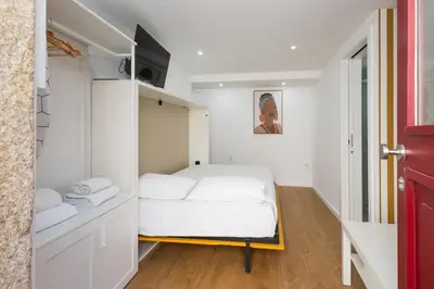 a small room with a white bed in it at Cozy Studios Porto Sao Lazaro in Porto