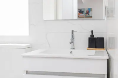 a white bathroom with a sink and a soap dispenser at Cozy Studios Porto Sao Lazaro in Porto